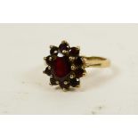 A 9ct gold and garnet dress ring set with central oval stone surrounded by ten small, round