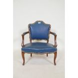 A vintage child's open armchair in the French style, with shaped back and arms, sprung leather