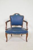 A vintage child's open armchair in the French style, with shaped back and arms, sprung leather