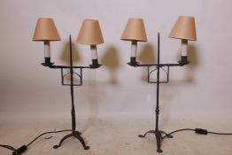 A pair of contemporary wrought metal two branch table lamps, raised on tripod supports, 22" high,