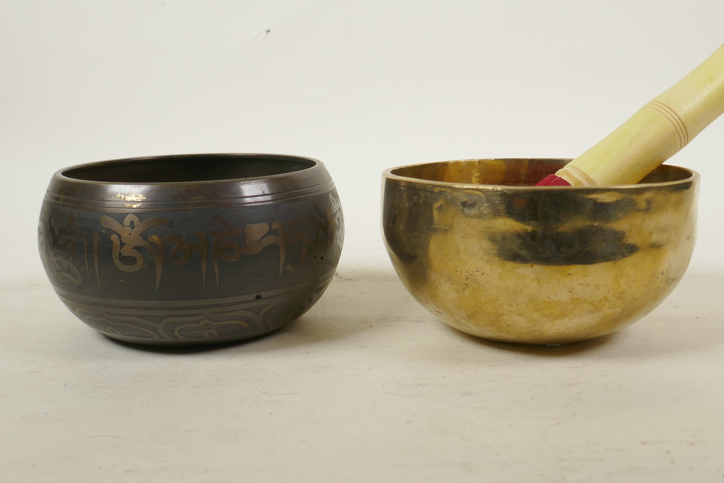 A Tibetan gilt bronze singing bowl, and another with character script decoration to exterior and