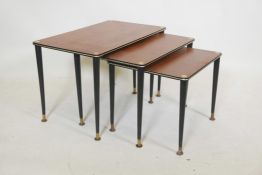 A mid century nest of three tables with teak tops, ebonised supports and brass feet, 24" x 15", 15½"