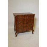 A small French style oak commode, shaped front and four long drawers with carved decoration and