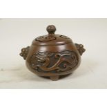 A Chinese bronze censer and cover with two lion mask handles, tripod feet and decorative dragon