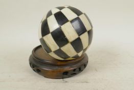 A Chinese carved hardwood vase stand, 5" diameter, and a sectional bone and shell ball, 4" diameter