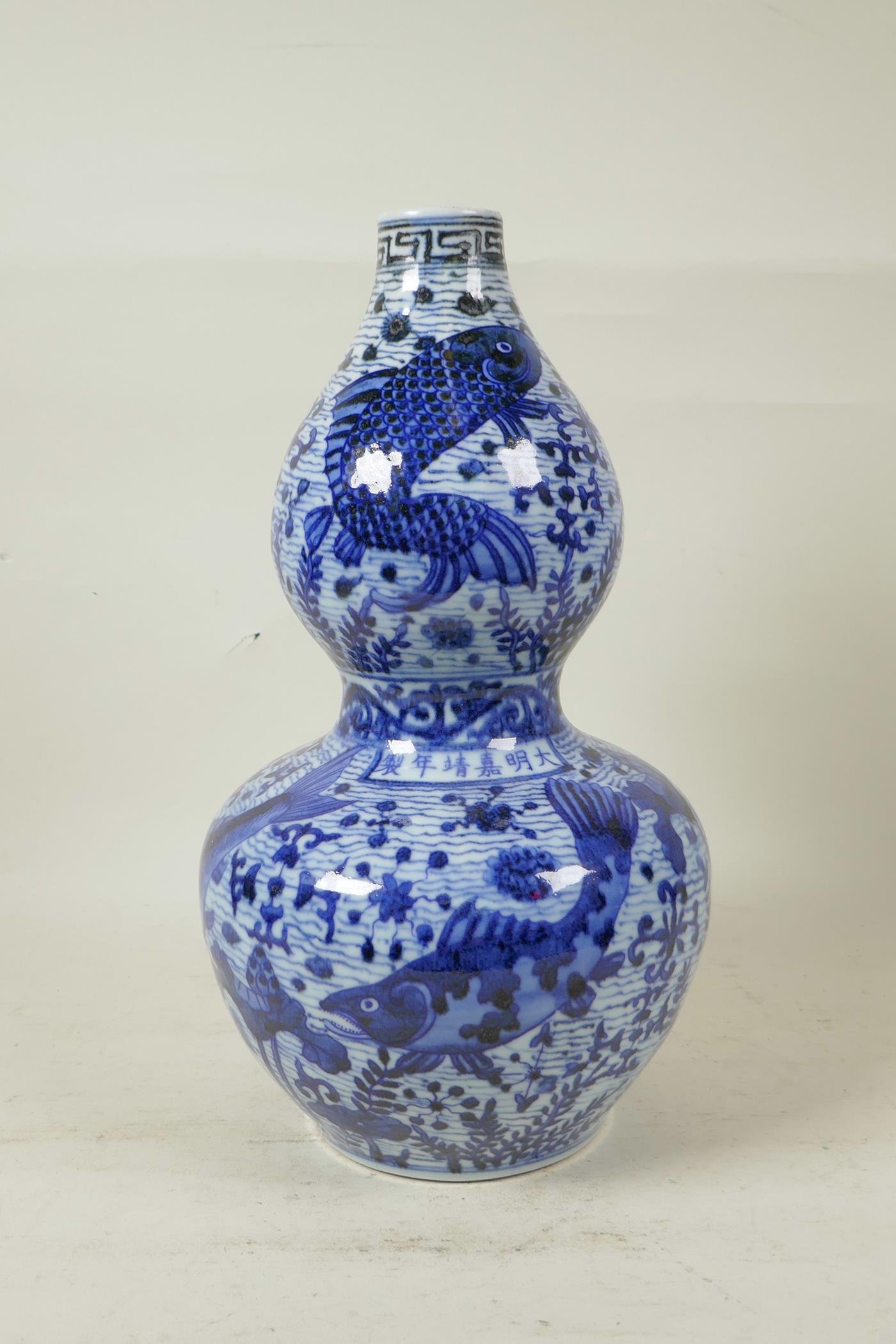A Chinese Ming style blue and white porcelain double gourd vase decorated with carp in a lotus pond,