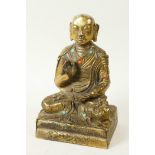 A Sino-Tibetan brass figure of Buddha seated in meditation having engraved decoration and set with