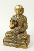 A Sino-Tibetan brass figure of Buddha seated in meditation having engraved decoration and set with