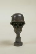 A bronze seal in the form of a skull in an army helmet, 1½"