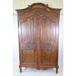 A French walnut armoire with floral carved decoration to the cornice and fielded panel doors