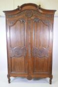 A French walnut armoire with floral carved decoration to the cornice and fielded panel doors