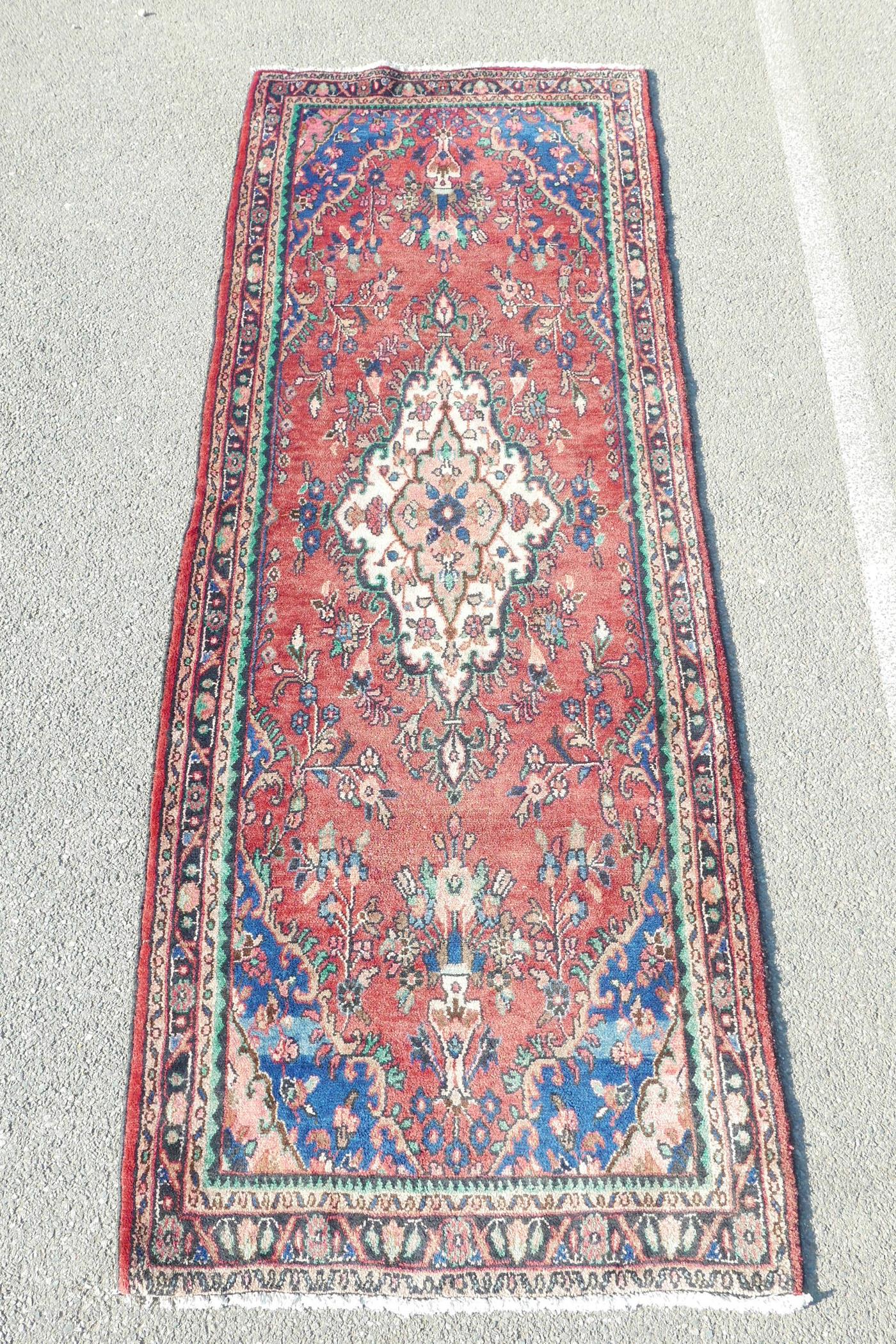 A full pile Sarouk runner with a traditional design on a red ground, 46" x 123"