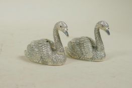 A pair of silver plated condiments in the form of swans, 2" long