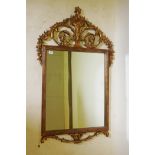 An ornate gilt framed rectangular wall mirror with carved top and bottom rails and a rib moulded