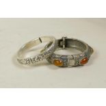 A Chinese white metal bangle decorated with the emblems of the eight Immortals, and another