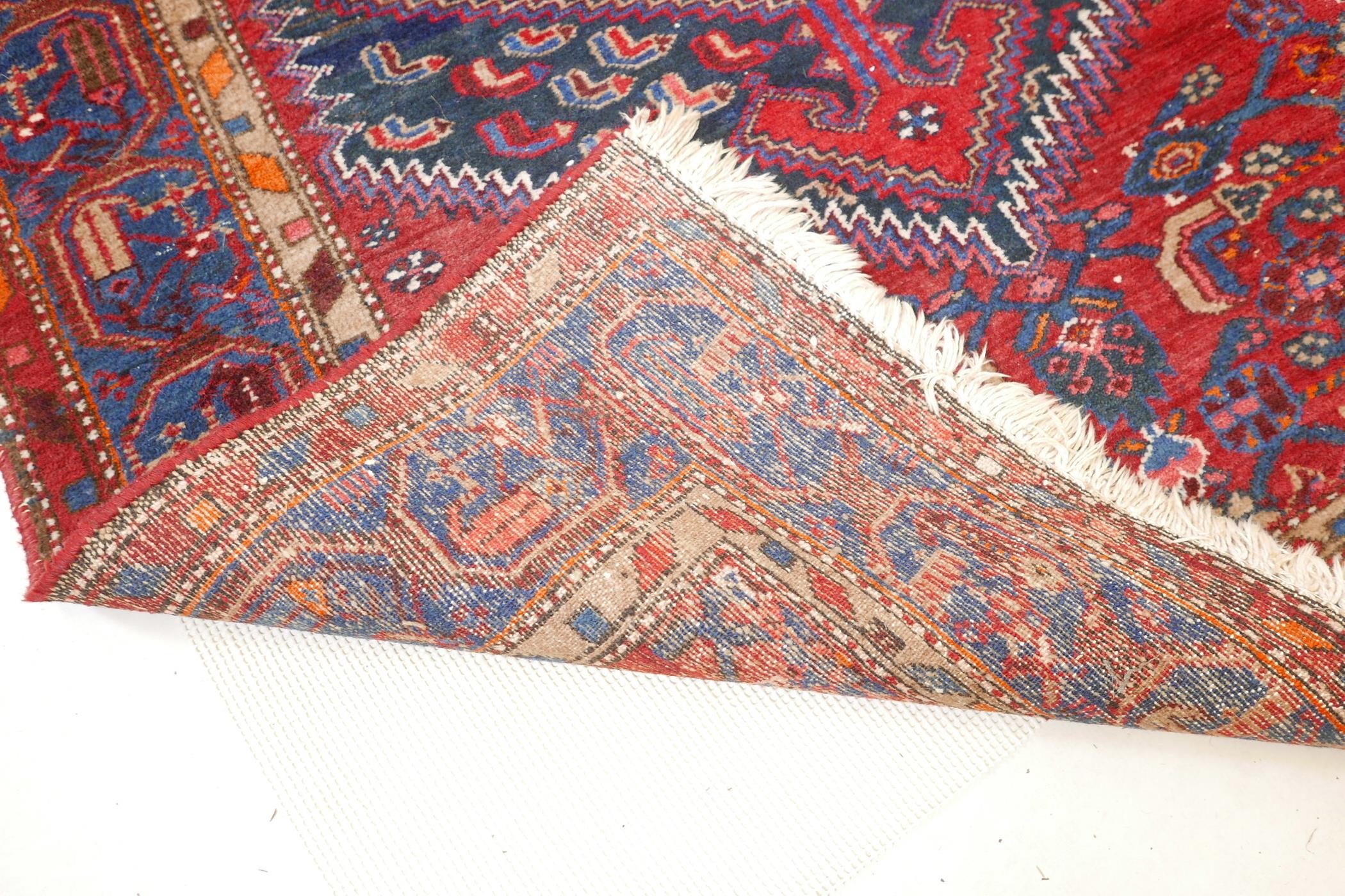 A Persian red ground wool carpet with a centralised medallion design on a blue border, 52" x 80" - Image 4 of 4