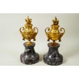 A pair of ormolu side urns with ram's mask decoration, mounted on marble socles, 10½" high