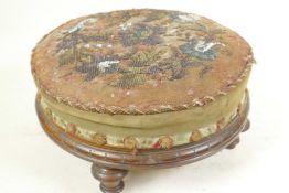 A C19th circular walnut footstool with carved decoration on four turned legs and having beadwork
