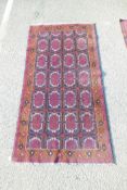 A Middle eastern rug decorated with a Bokhara style design on a blue field with red and ochre