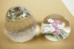 A pink and white florally decorated paperweight, signed, 3" diameter, together with a faceted