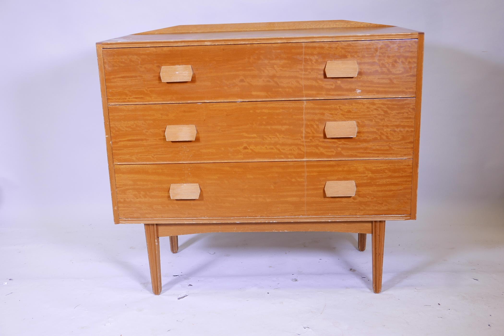 A mid C20th chest of three long drawers raised on ribbed, tapered supports, 42" wide, 37" long,