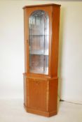 A contemporary teak illuminated corner display cabinet with single cut glass door, and mirror