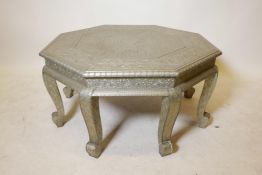 An Indian octagonal topped low table with repousse white metal decoration, raised on eight shaped