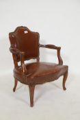 A vintage child's open armchair in the French style, with shaped back and arms, sprung leather