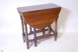 An early C20th oak gateleg action drop leaf table, raised on barleytwist supports, 30" x 14" x 28"