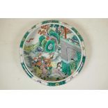 A Chinese famille verte porcelain dish with a rolled rim, decorated with warriors on horseback in