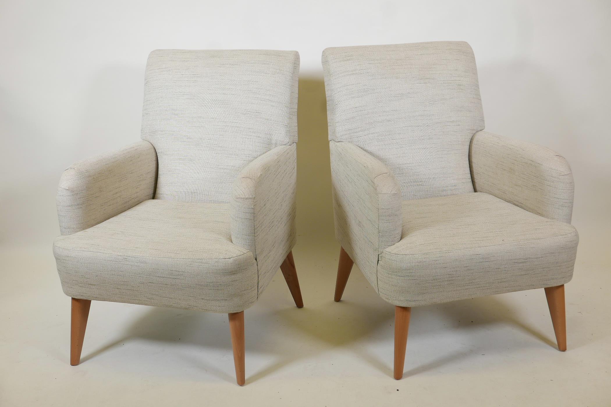 A pair of contemporary armchairs raised on splay supports, 35" high