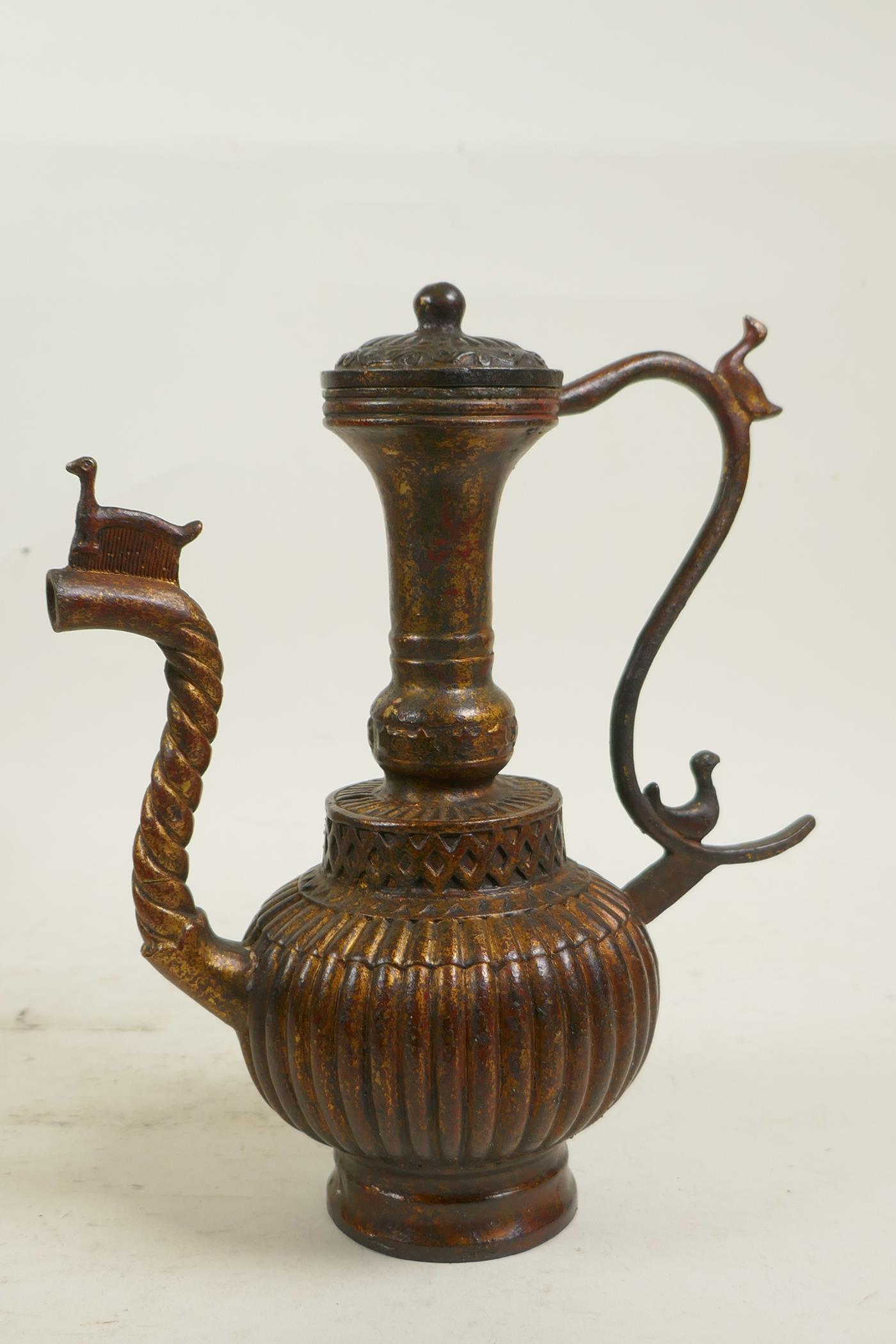 An Islamic bronze ewer with a ribbed body, twist spout and gilt patina, 9" high - Image 6 of 6