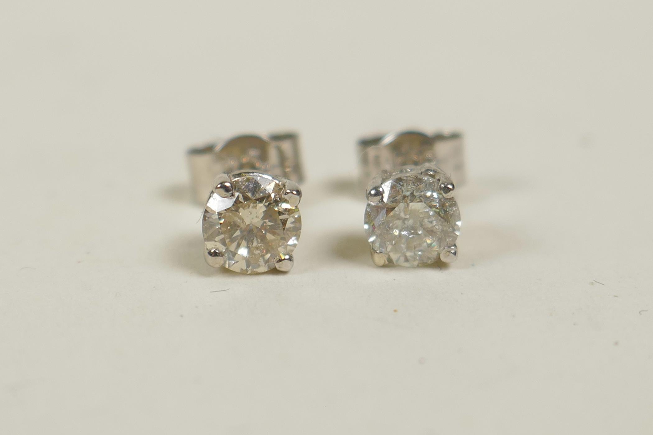 A pair of 14ct white gold diamond stud earrings, 64 points