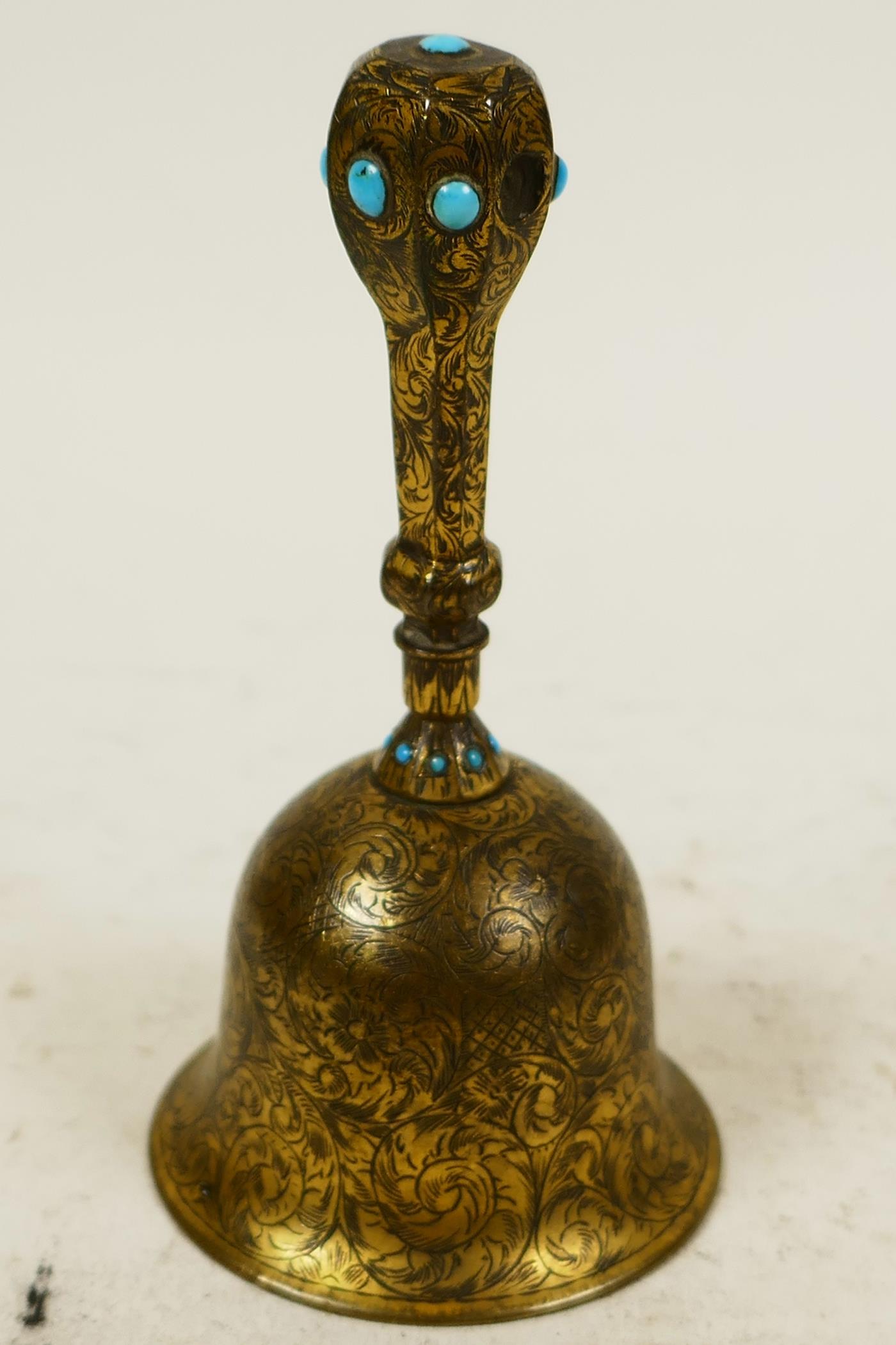 A small Oriental brass table bell with engraved floral decoration and inset with turquoise beads, 4"