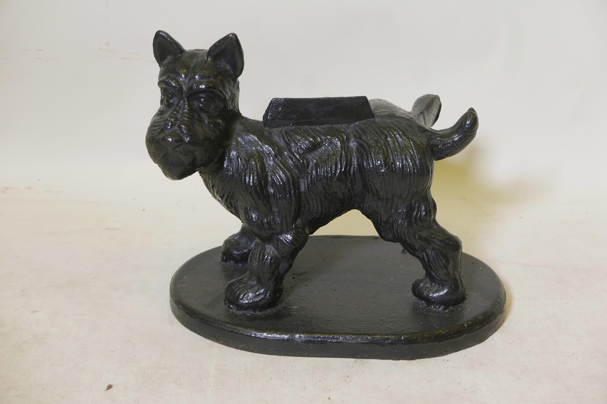 A vintage painted cast iron bootscraper in the form of an Angus terrier cocking his leg, 16" x 14"