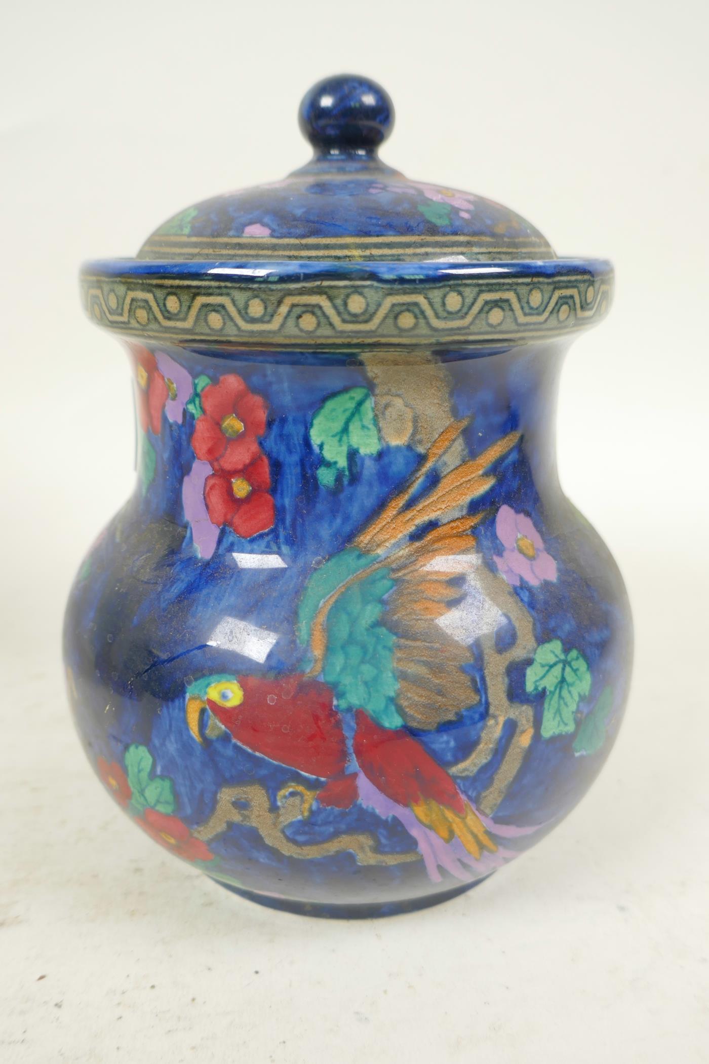 A Losol ware Andes pattern jar and cover decorated with parrot and flowers on a lustre blue
