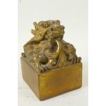 A Chinese gilt bronze seal, the top cast as a mythical creature with coral set eyes, 3½" square