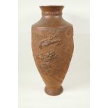 A Japanese red earthenware urn shaped vase with embossed and carved decoration of dragons, 18½" high