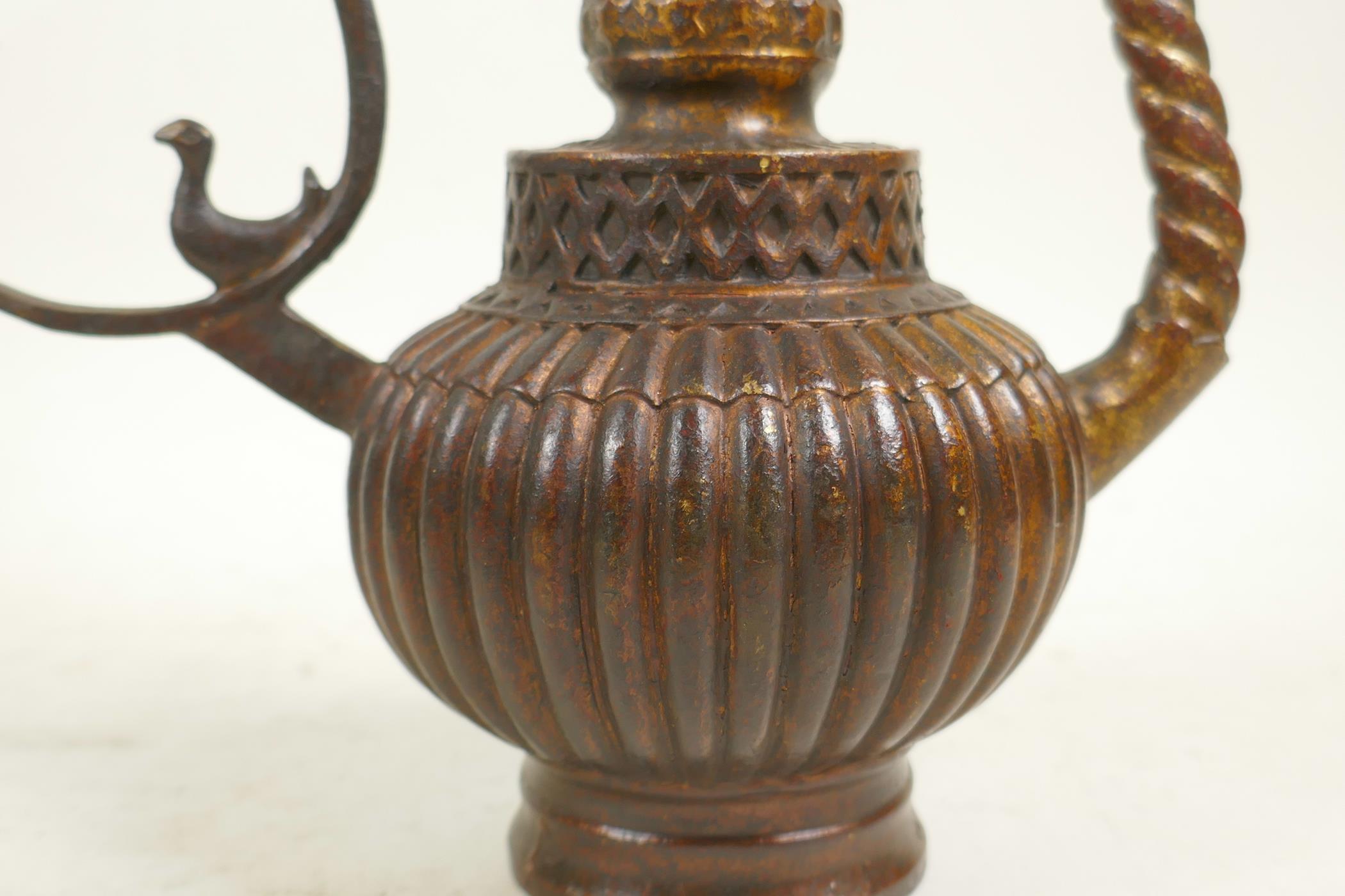 An Islamic bronze ewer with a ribbed body, twist spout and gilt patina, 9" high - Image 2 of 6