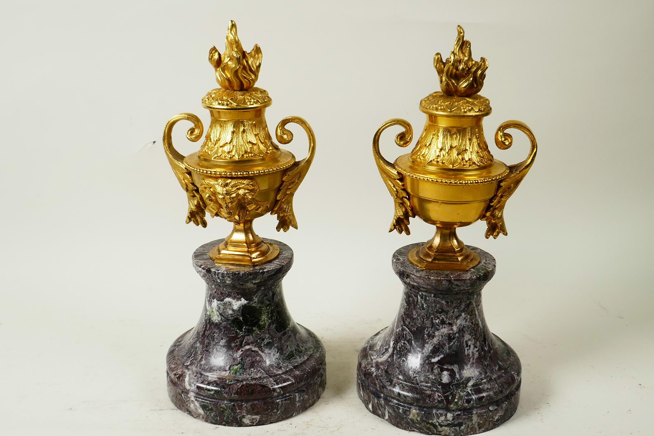 A pair of ormolu side urns with ram's mask decoration, mounted on marble socles, 10½" high