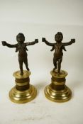 A pair of bronze cherubs cast with outstretched arms mounted on French marble and ormolu Empire