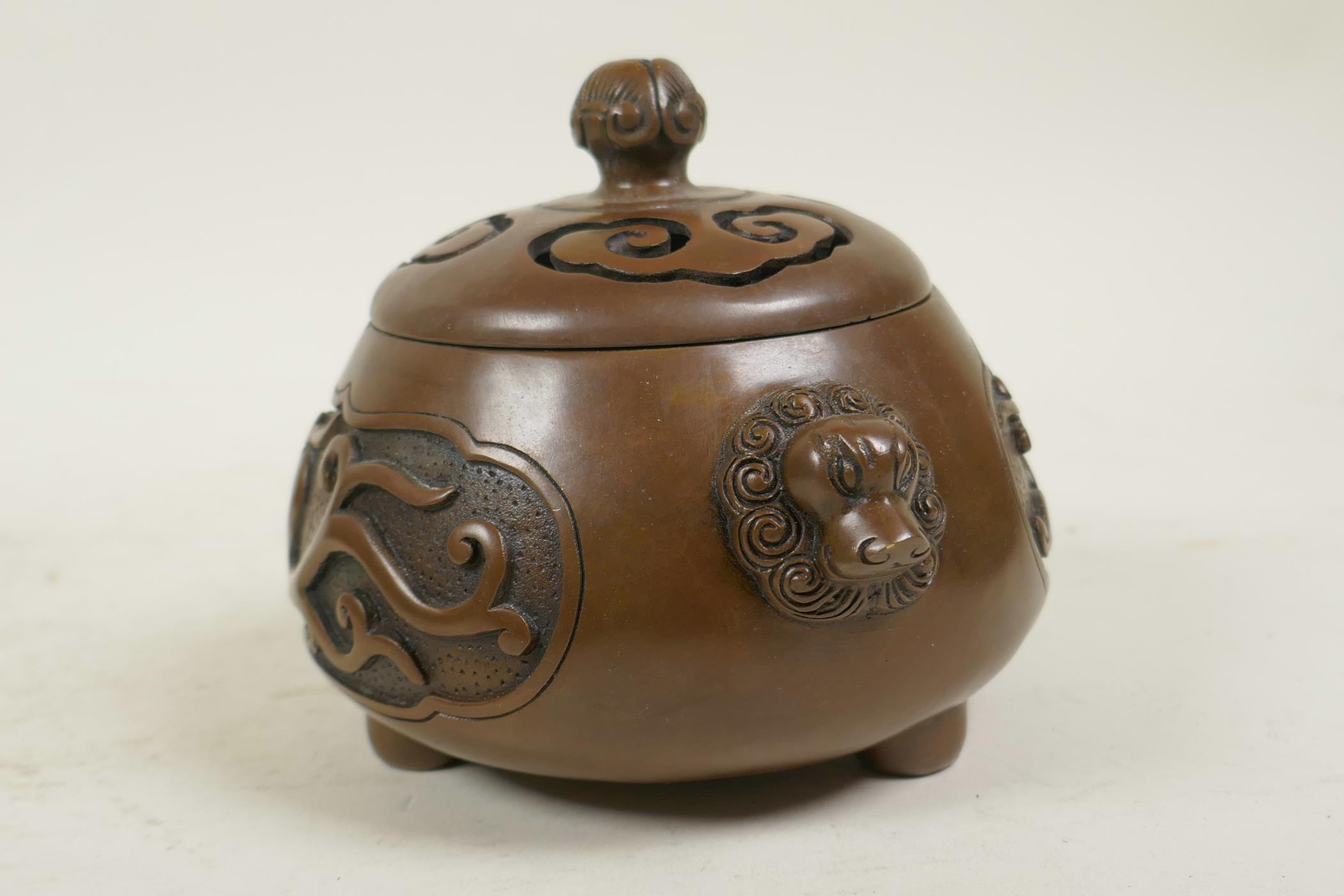 A Chinese bronze censer and cover with two lion mask handles, tripod feet and decorative dragon - Image 2 of 4