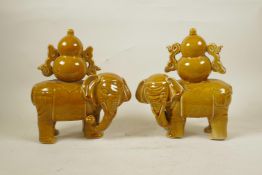 A pair of ochre glazed porcelain figures of elephants carrying double gourd vessels, 10" high