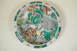 A Chinese famille verte porcelain dish with a rolled rim, decorated with warriors on horseback in