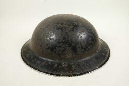 An original WWII Brodie military steel helmet issued for the Home Guard, missing chin strip and