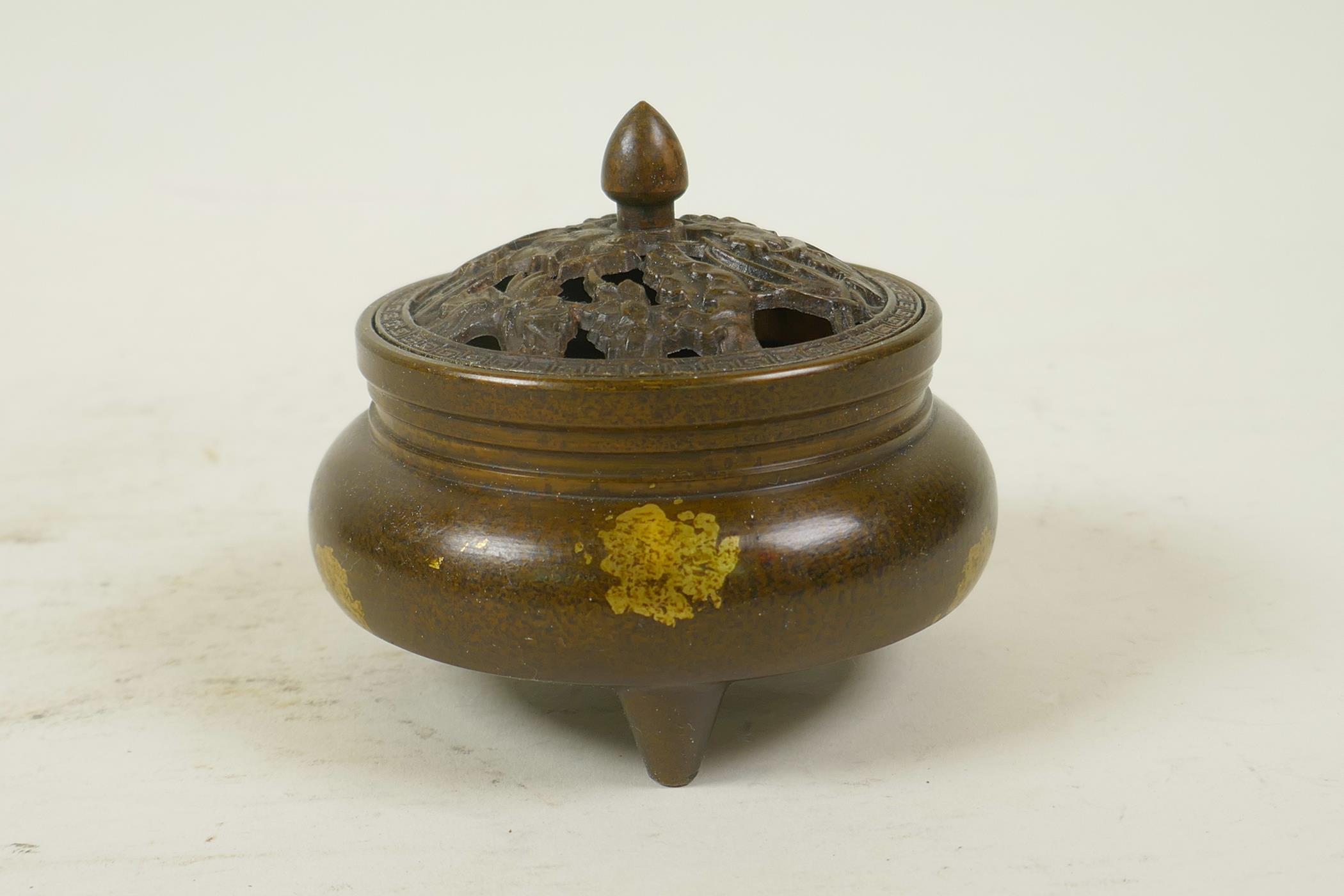 A Chinese gilt splash bronze censer and cover on tripod feet, the pierced cover decorated with