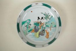 A Chinese famille verte porcelain charger decorated with women and children playing music in a
