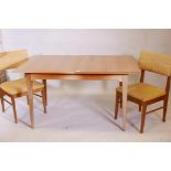 A 1970s teak extending dining table on square tapering supports, with built in leaf, and two