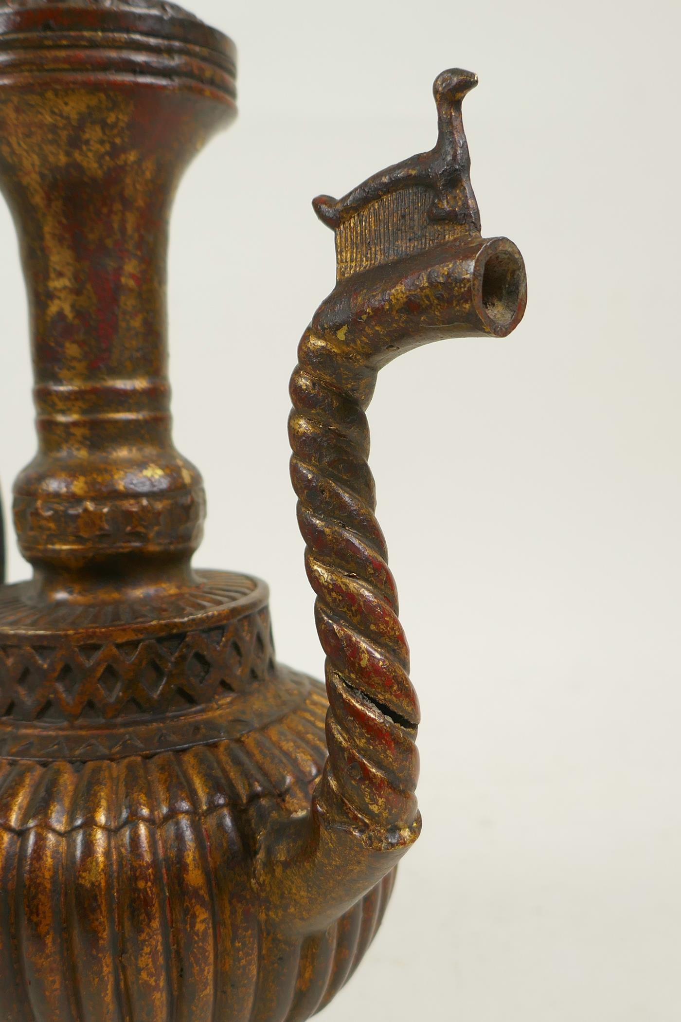 An Islamic bronze ewer with a ribbed body, twist spout and gilt patina, 9" high - Image 4 of 6