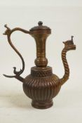 An Islamic bronze ewer with a ribbed body, twist spout and gilt patina, 9" high